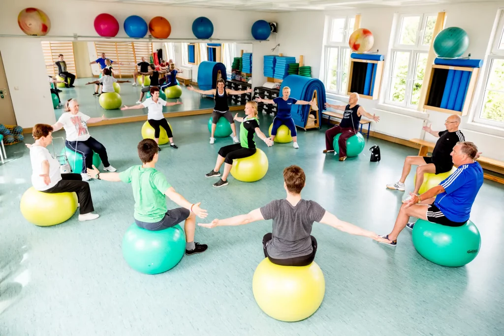 Männer und Frauen jedes Alters sitzen auf Gymnasticbällen im Kreis und trainieren © www.AndreasLander.de